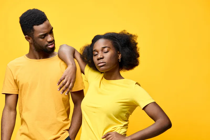 A young Black couple in matching yellow outfits expressing love and confidence against a bright yellow background Emotions of joy, harmony, and connection are highlighted here