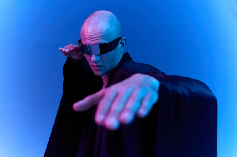 Futuristic man wearing sunglasses striking a dynamic pose in a vibrant light. The bold colors create an energetic vibe, perfect for modern design concepts.