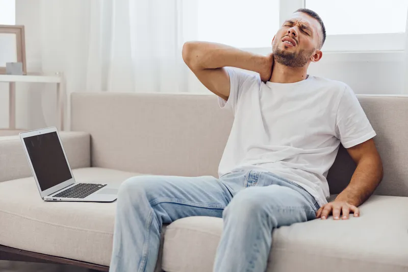 Man experiencing discomfort while working from home, demonstrating emotional strain, blurred work-life balance, and the impact of modern technology on mental health.