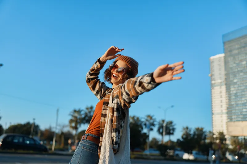 woman joy candid urban carefree smile captured at golden hour glow, authenticity and mindful living in an emotional storytelling candid lifestyle portrait with sunglasses and warm sunlight