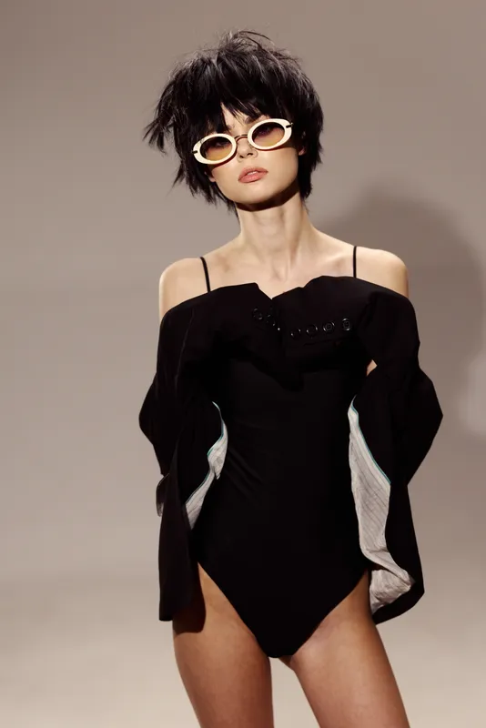 fashion woman wearing black outfit and white sunglasses with confident pose on beige background