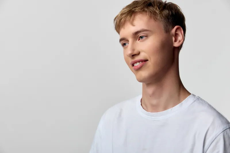 Man, smile, casual, tshirt, white, studio, relaxed vibe and friendly look in bright setting for lifestyle fashion and simple branding usage