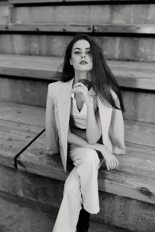 Confident businesswoman in a stylish suit, showcasing professional elegance and determination in a modern monochrome setting.