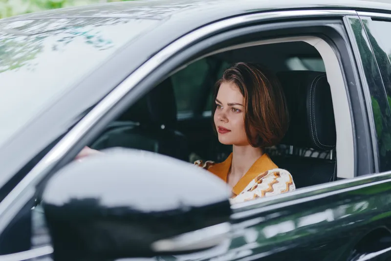 Car, driver, woman, smile a cheerful woman sits in the driver's seat with a relaxed posture, hand on the steering wheel, radiating joy, confidence, and readiness for a smooth journey.