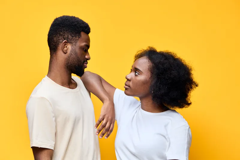A joyful couple sharing an intimate moment, showcasing love and connection against a vibrant yellow background, expressing emotions of affection and happiness