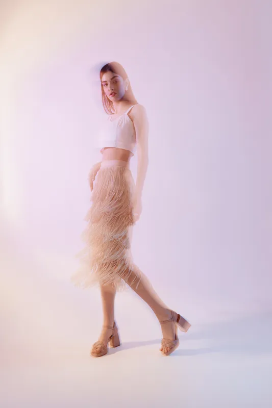 Young woman in stylish fashion outfit poses in soft light with blurred effect. Concept of beauty, elegance, fashion, and modern style in studio environment.