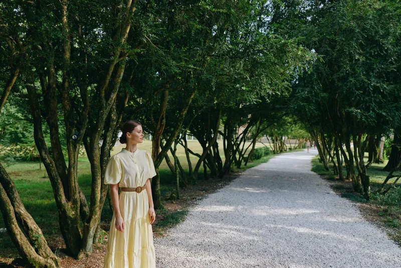 Woman in yellow dress on trees lined path inclusive