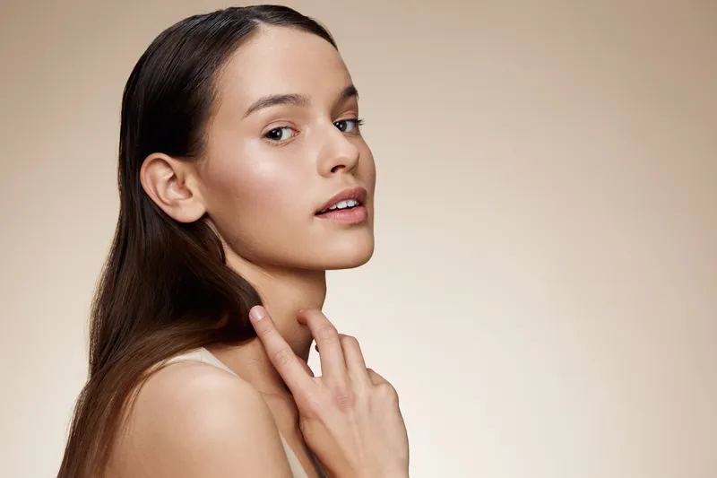 Elegant close up portrait of a young woman with natural makeup and smooth skin, showcasing beauty and confidence against a soft, neutral background