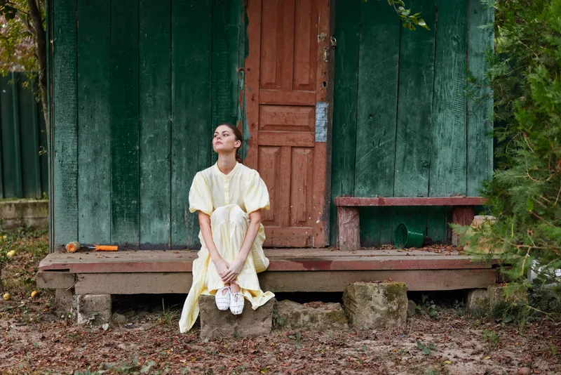 woman dress porch vintage rural shoes authenticity inclusivity woman in yellow dress sits on wooden step