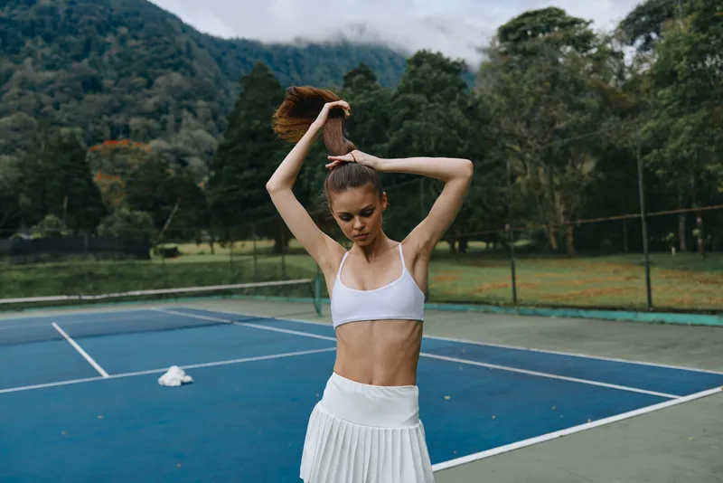 A young athletic woman stretching on a tennis court, showcasing a fit physique and active lifestyle in a vibrant outdoor setting, ideal for fitness and well being concepts