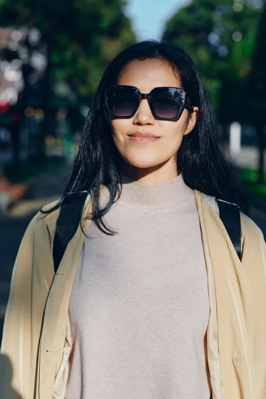 Sunglasses, woman, outdoors, fashion, style, sunlight, casual, backpack, jacket, sweater, urban street photography with accessory mood and confident expression in bright daytime lighting