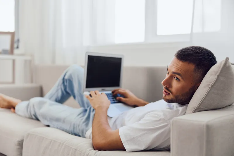 Thoughtful man working remotely from home, embodying themes of work-life blur and personal space, navigating the complexities of modern living.