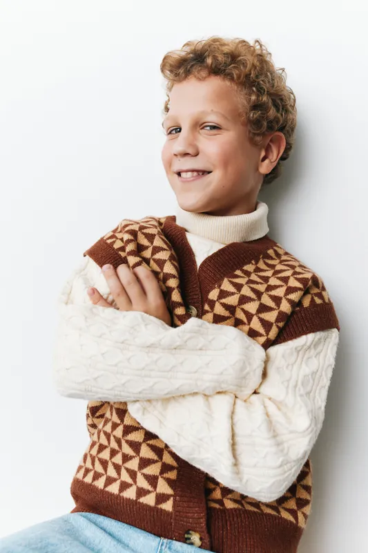 Authentic lifestyle portrait of a schoolbound child in a cozy knit sweater, exuding warmth, confidence, and playful charm; a candid moment that highlights everyday youth and simple joy.