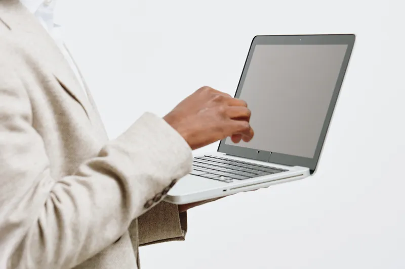 Businesswoman using laptop computer in office, professional work environment, modern technology, casual attire, neutral background, focused on digital device, workspace setup, professional lifestyle c