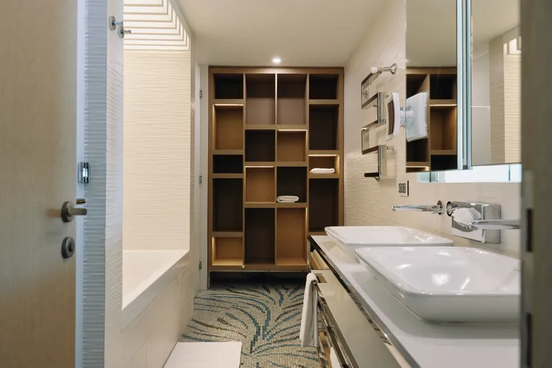 Bright bathroom with a modern vanity, open wood shelving, sink and tub, towel rail, airy lighting and neutral tones creating a calm spa like atmosphere in a contemporary home.