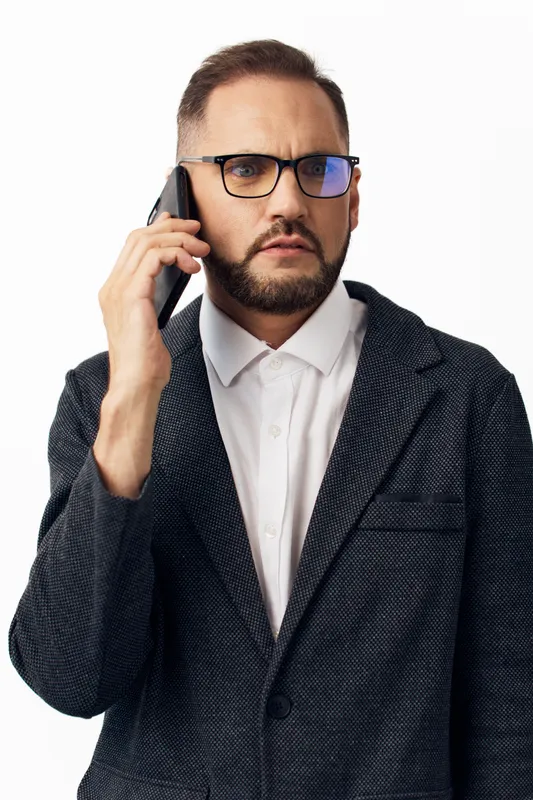 A focused business professional man on a call, isolated on a clean colored background, exuding confidence and concern while negotiating or making a critical decision.