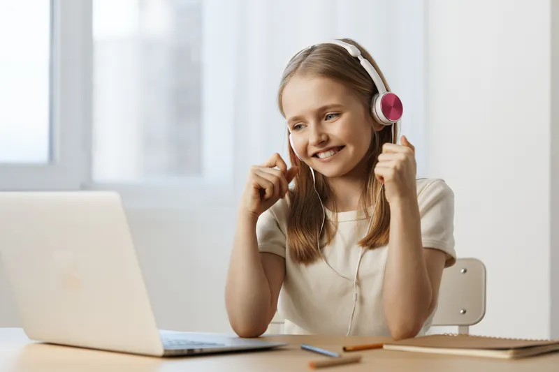 Happy girl with headphones enjoying online learning at home, bright colors and modern decor reflecting a cheerful atmosphere