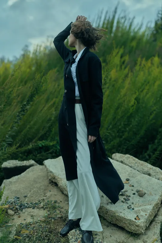 Fashion outdoors wind dress coat movement landscape dramatic natural silhouette stance with wind swept hair on rugged rocks, creative outdoor style and cinematic mood