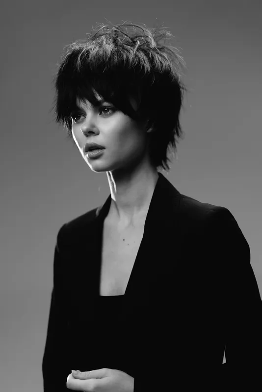 Black and white portrait of a young woman with short hair wearing a black jacket with a serious expression.