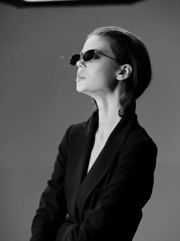 Stylish woman wearing sunglasses and a black jacket in black and white portrait with a serious expression and modern look