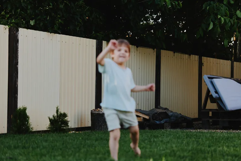 Joyful boy playing outdoors in a sunny garden, enjoying the summer atmosphere with vibrant greenery and a relaxed environment.