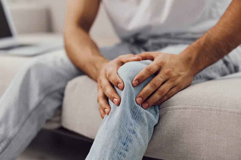 Man sitting on a couch, experiencing AI anxiety and emotional vulnerability, reflecting on work-life blur and the challenges of modern living.