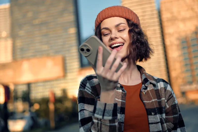 woman phone smile city candid authenticity golden lifestyle young woman laughing on smartphone in urban street during warm golden hour glow, mindful living and emotional storytelling moment
