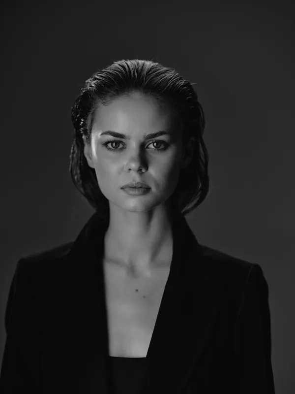 Black and white portrait of serious woman with wet hair in dark clothing on dark background