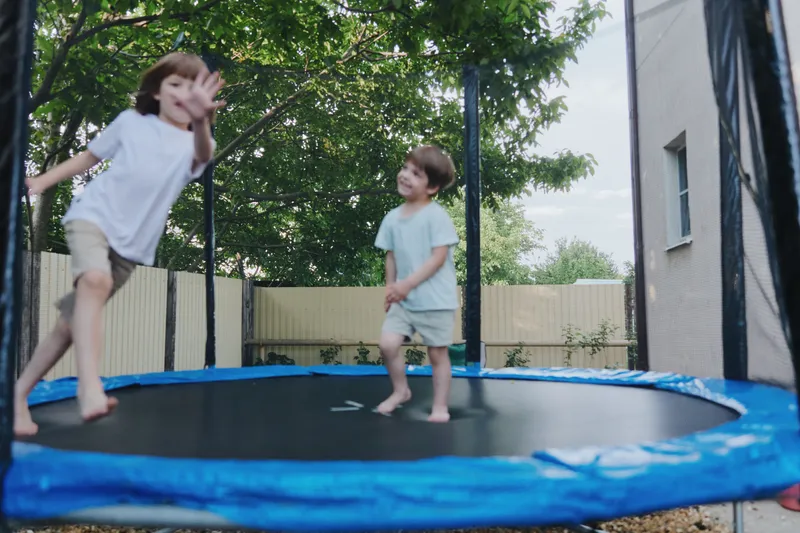 Joyful kids jumping on a trampoline, enjoying a sunny day outdoors with laughter and smiles. Perfect for capturing playful moments and childhood excitement.