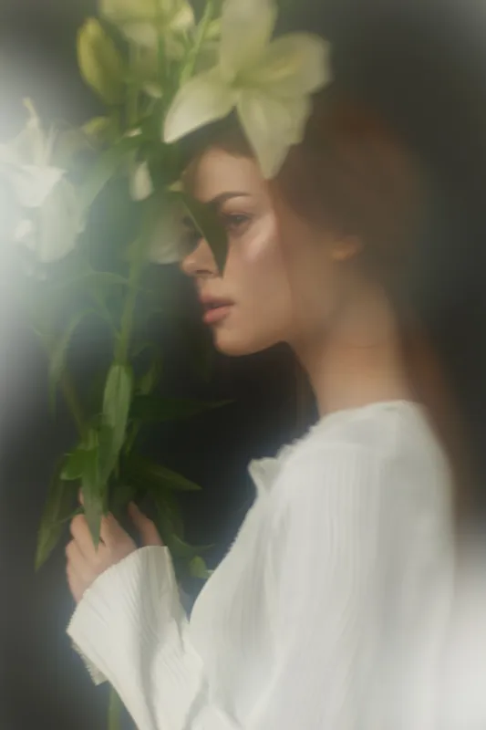 Ethereal portrait of a young woman holding white lilies, embodying serenity and beauty, soft focus, ideal for concepts of nature, femininity, and tranquility