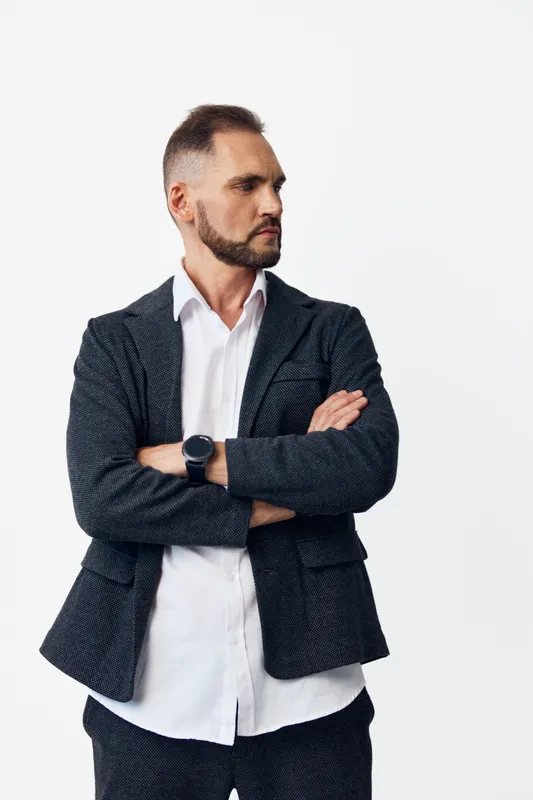 A business professional man stands with arms crossed, radiating confidence and focus. On an isolated colored background, he conveys determination, calm control, and leadership, ready to tackle tasks