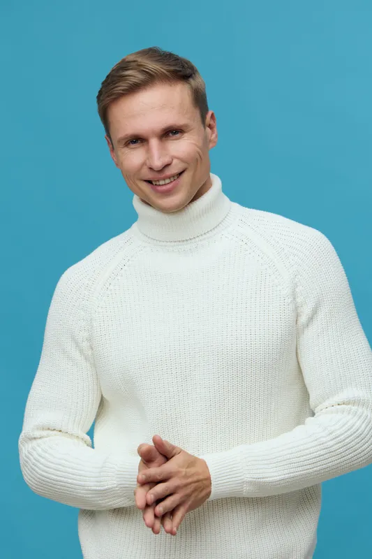 Smiling young caucasian man wear white turtleneck sweater look camera clap hands isolated on blue background cheerful casual male portrait lifestyle concept