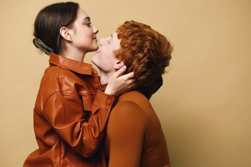 Couple, romance and affection with young man and woman hugging and smiling for love and relationship. Togetherness, emotional connection and intimacy with gentle touch in studio indoors.