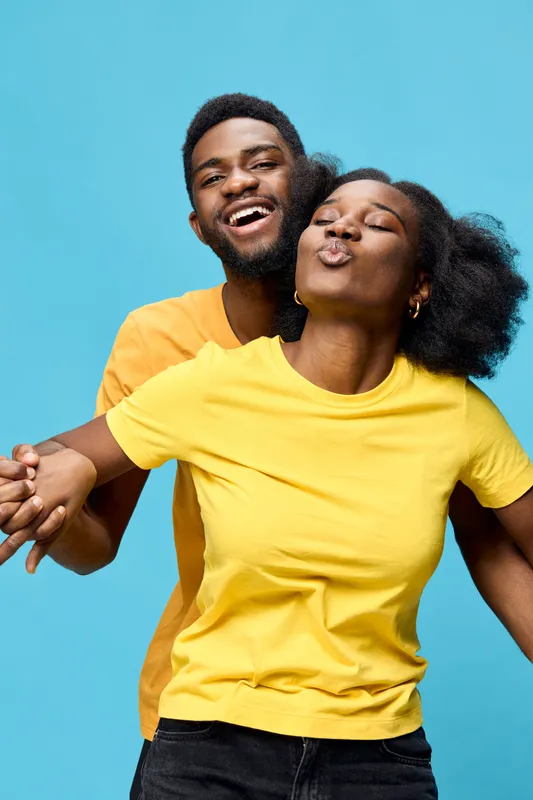 Happy couple wearing colorful t shirts against a blue background, showcasing joy and connection, ideal for concepts of love and relationships