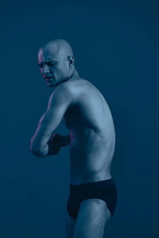 Athletic man posing confidently in a dramatic black and white shot, highlighting his muscular physique and strong emotions. A striking representation of male strength.