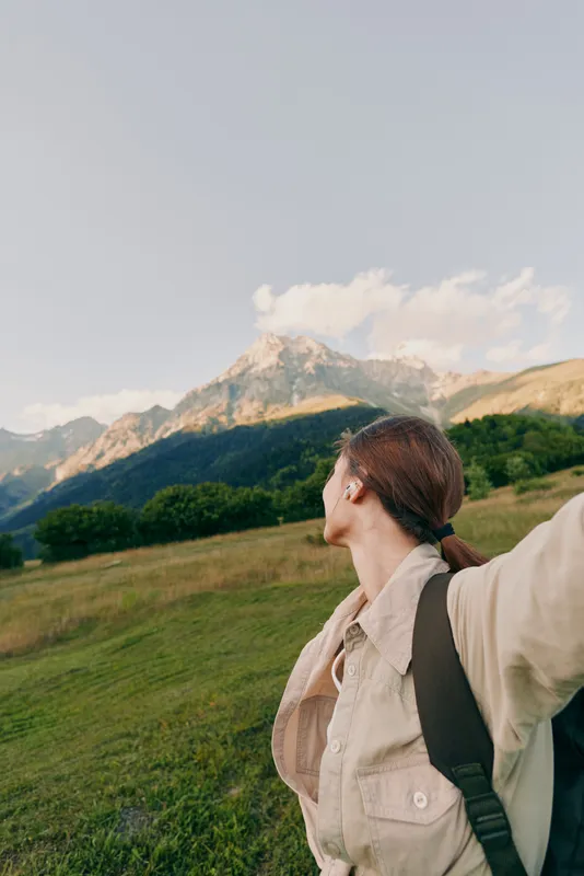 Traveler with backpack gazing toward distant mountains on a sunny day, expansive valley, outdoor exploration, nature, adventure, serenity, wanderlust, simple living, woman lifestyle