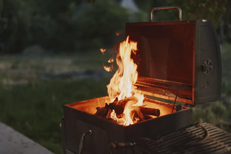 Grilling outdoors with flames rising in a barbecue, perfect for summer gatherings and outdoor cooking sessions with friends and family