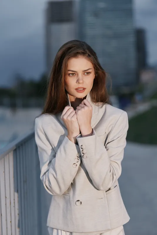Confident woman in a business outfit outdoors with a city skyline, exuding professionalism and determination, ideal for corporate imagery.