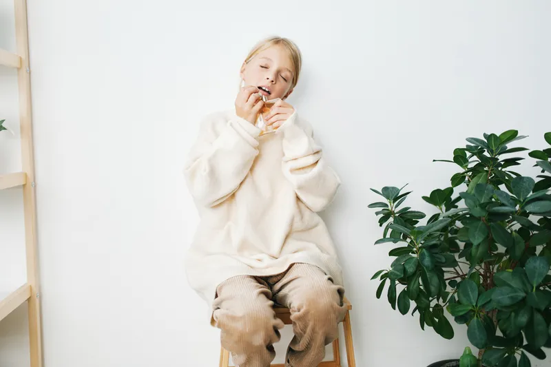 Authentic lifestyle image of a young student in a cozy sweater, portraying a candid moment of relaxation, confidence, and everyday comfort in a calm home setting that communicates authentic lifestyle