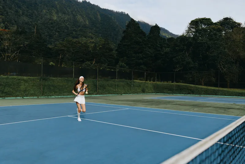 Young athletic woman playing tennis on a blue court in nature, showcasing energy, focus, and passion for the sport