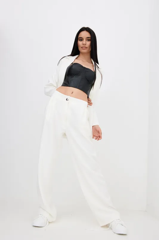 woman posing confidently in modern white pants and black corset top, minimalistic background, stylish casual outfit, long dark hair, natural look