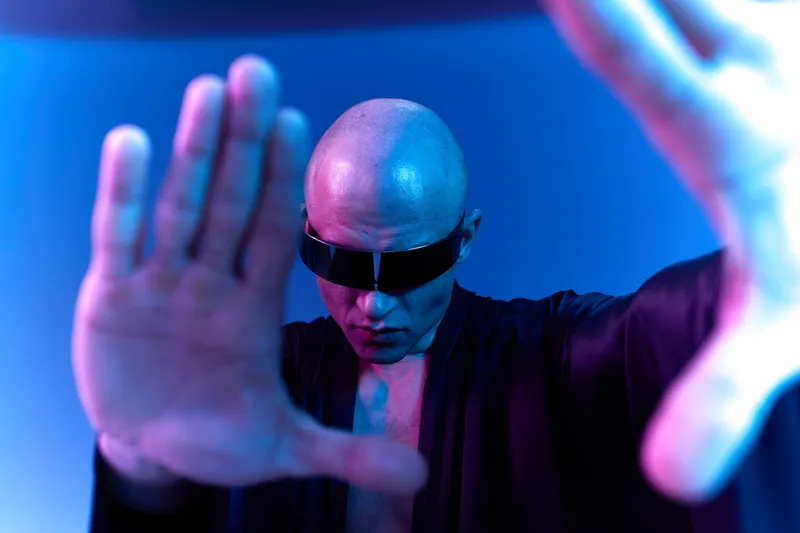 Futuristic man in black attire showcasing confidence and strength, with a unique neon lighting effect. Image features contrasting shadows and cool tones, black and white aesthetics.