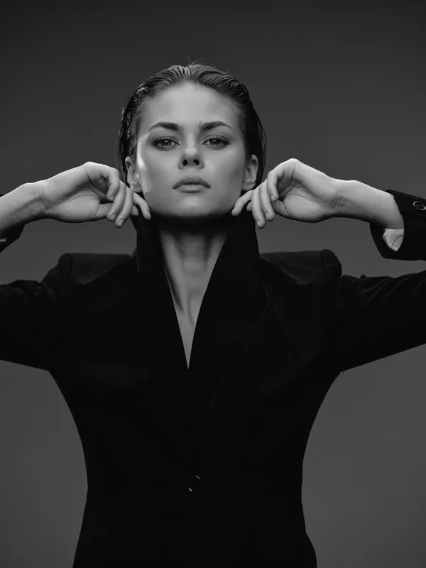 Black and white portrait of a confident woman with wet hair wearing a dark jacket with high collar
