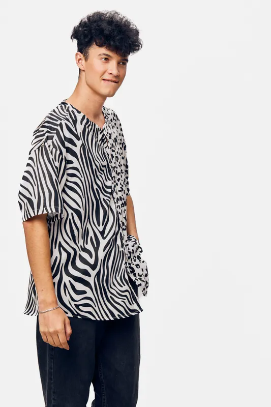 young man wearing a zebra print shirt standing against a white background, casual fashion style with a relaxed and confident expression