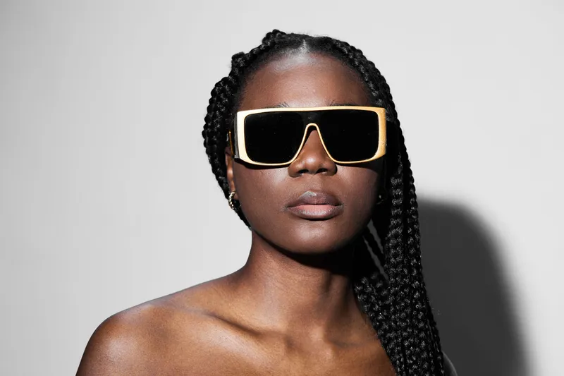 Stylish African woman with braided hair wearing oversized sunglasses, exuding confidence and elegance, perfect for fashion branding and summer campaigns
