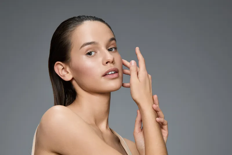Natural beauty portrait of a young woman with flawless skin, minimal makeup and a calm expression, showcasing healthy skin care and self care concepts