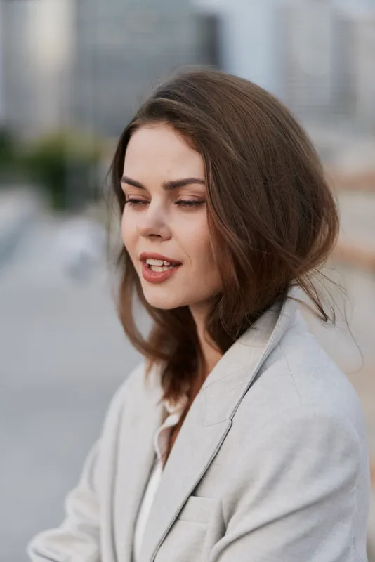 Woman in beige blazer with contemplative expression outdoors, emotional portrait of young Caucasian woman in soft natural light, fashion business concept