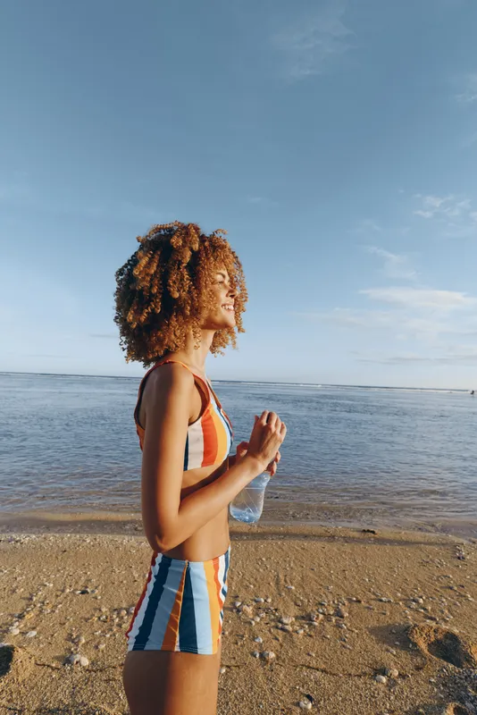 Woman, beach, ocean, yoga, meditation, summer, curly, hair, standing on sandy shore in daylight, hands in prayer pose, relaxed posture, calm wellness and balance
