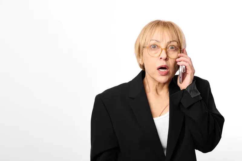 Mature woman portrait, business suit, phone call, glasses, surprised shocked expression, studio white background, communication, female agent, copy space