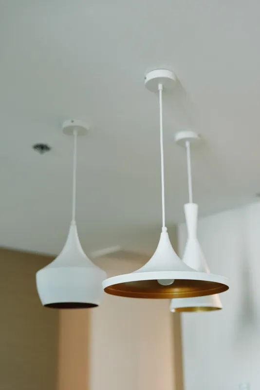 Modern pendant lights hang from a white ceiling with warm glow, minimalist interior decor and contemporary home lighting providing soft ambient illumination in a stylish space.